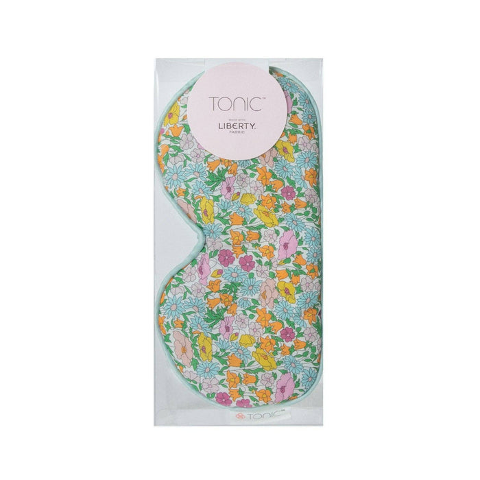 A floral printed Liberty of London eye mask with a satin back, packaged in a clear plastic case.