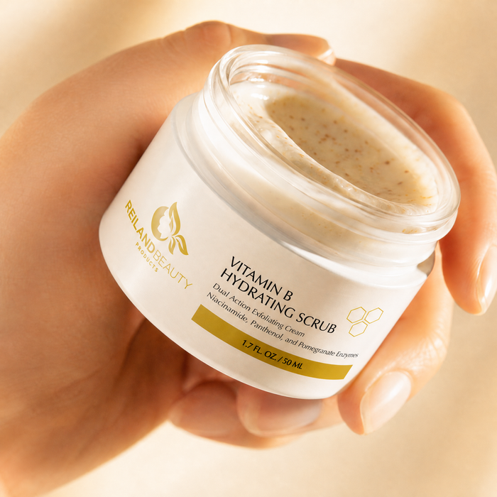 Hand holding open jar of Reiland Vitamin B Hydrating Scrub, showing the exfoliating cream texture up close