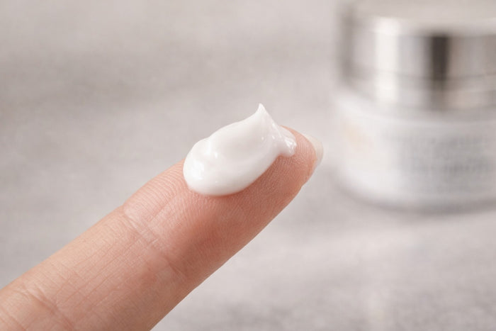 Close-up of a fingertip holding a smooth, creamy skincare texture from the Reiland Advanced Age Reverse System, shown against a soft neutral background to highlight consistency and application feel.