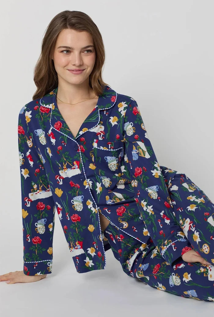 Woman wearing a blue pajama set with Alice in Wonderland print on a white background