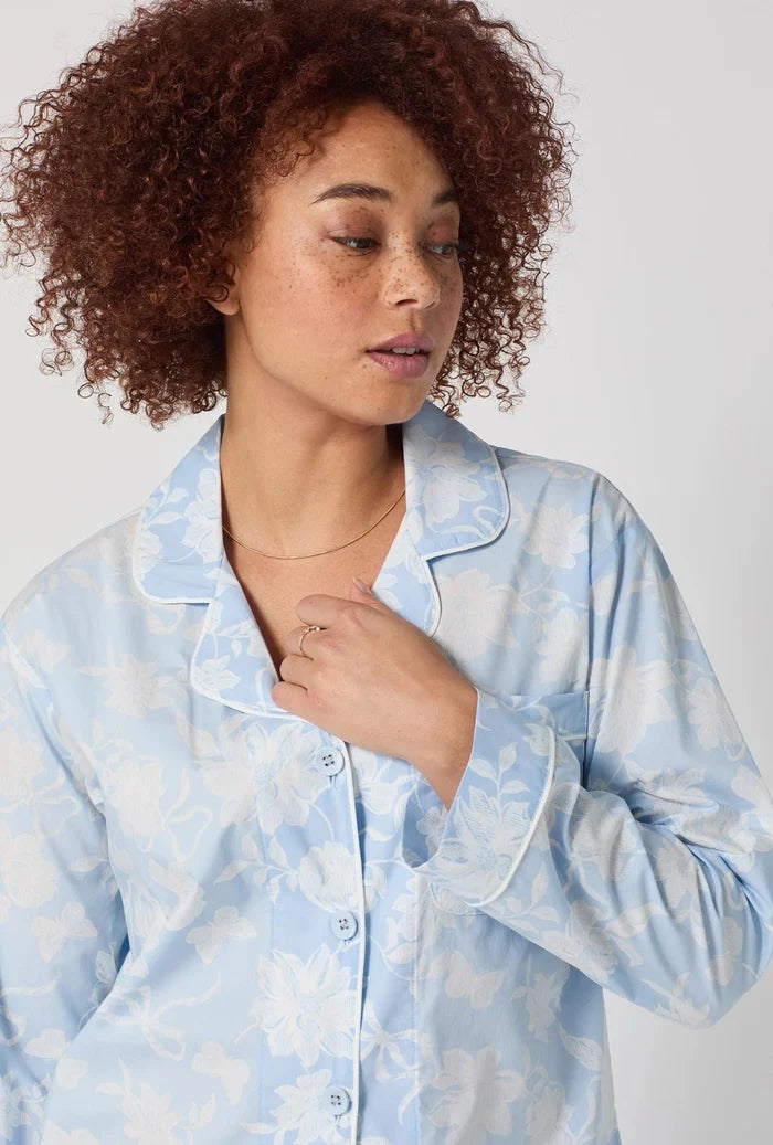 Woman wearing a light blue pajama top with a subtle pattern on a plain background