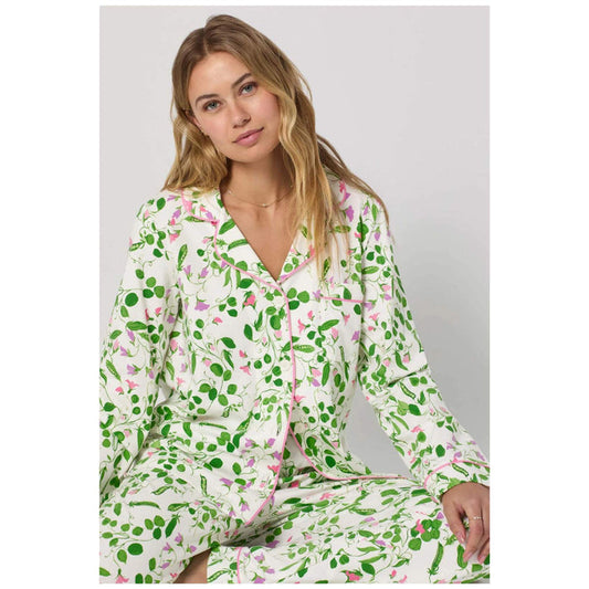 Woman wearing a green and pink patterned pajama set on a plain background