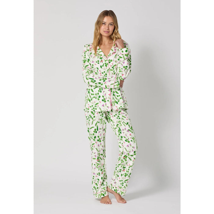 Woman wearing a green floral pajama set on a white background