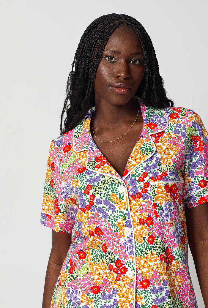 Woman wearing a colorful floral shirt against a white background