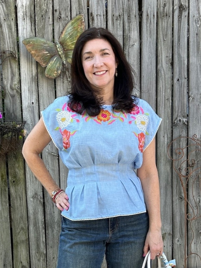 Brighten your wardrobe with this charming cap sleeve top featuring a serene light blue base adorned with vibrant embroidered florals in hues of pink and orange. The fitted, cinched waist pairs beautifully with a flattering peplum silhouette.&nbsp;

Tara is wearing a size Medium.

Material: 100% Polyester

Care Instructions: Gentle cool hand wash cold, dry flat
