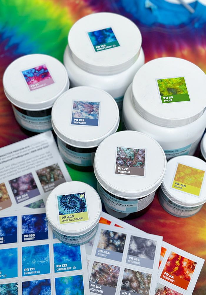 Full-color Ice Dye sticker sheets placed on  lids for corresponding dye containers from Dharma Trading Co. on a rainbow background.
