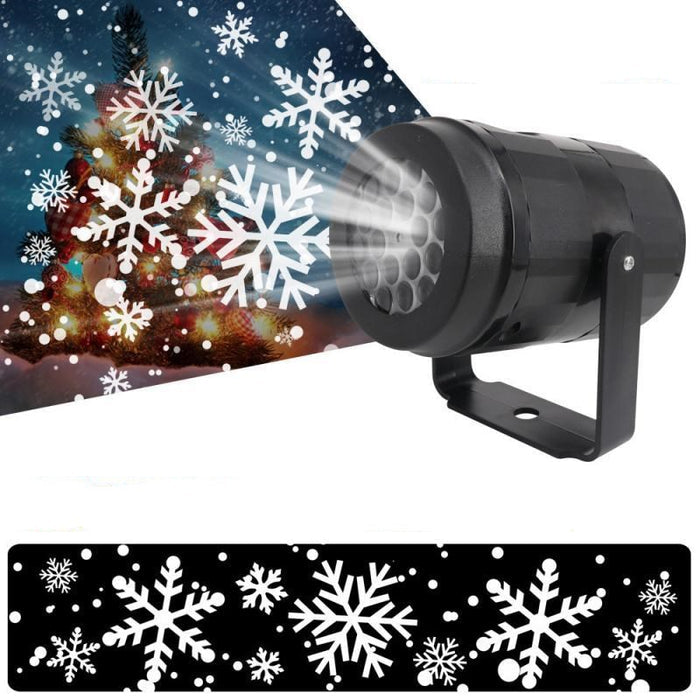 Snowflake projector emitting snowflakes onto a wall with a Christmas tree in the background.