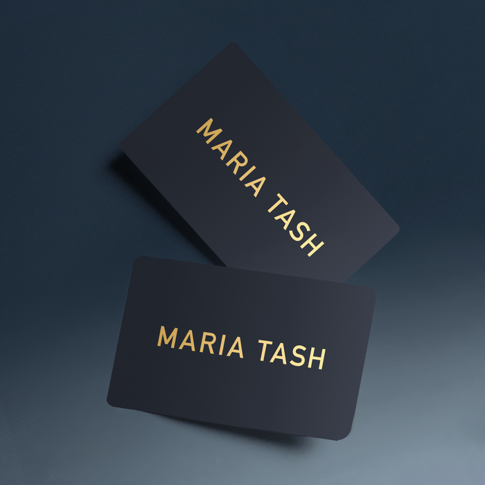 Two physical MARIA TASH gift cards with brand name in gold lettering on a gray gradient background