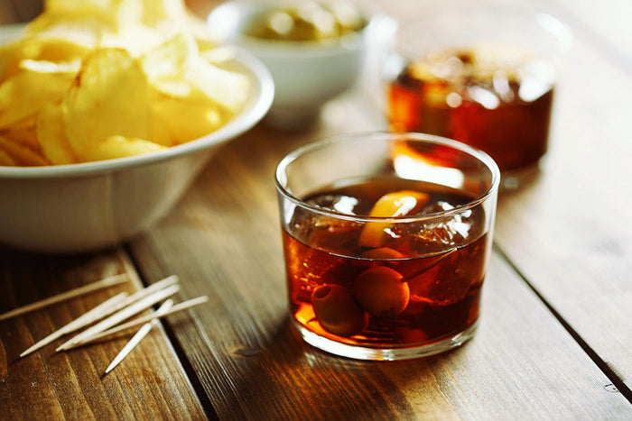 Aperitivo drink in rocks glass with ice cubes, on wooden table