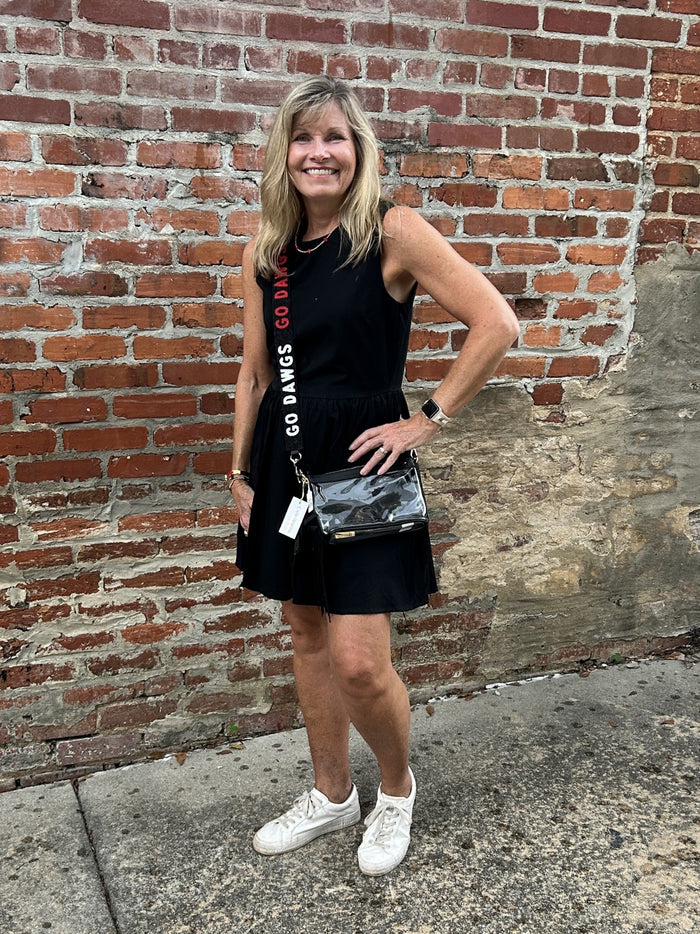 This black sleeveless mini dress offers a flattering silhouette that effortlessly enhances your figure. Perfectly lined for comfort, it features convenient side pockets to keep essentials close. Whether you're gearing up for game day or planning a stylish evening out, this dress combines practicality with chic appeal to keep you looking and feeling confident.

Carolee is wearing a size Small. She has accessorized with our Gold Beaded Necklace w/ Small Crosses (red), Bag/Purse Straps: Game Day Beaded (GO DAW