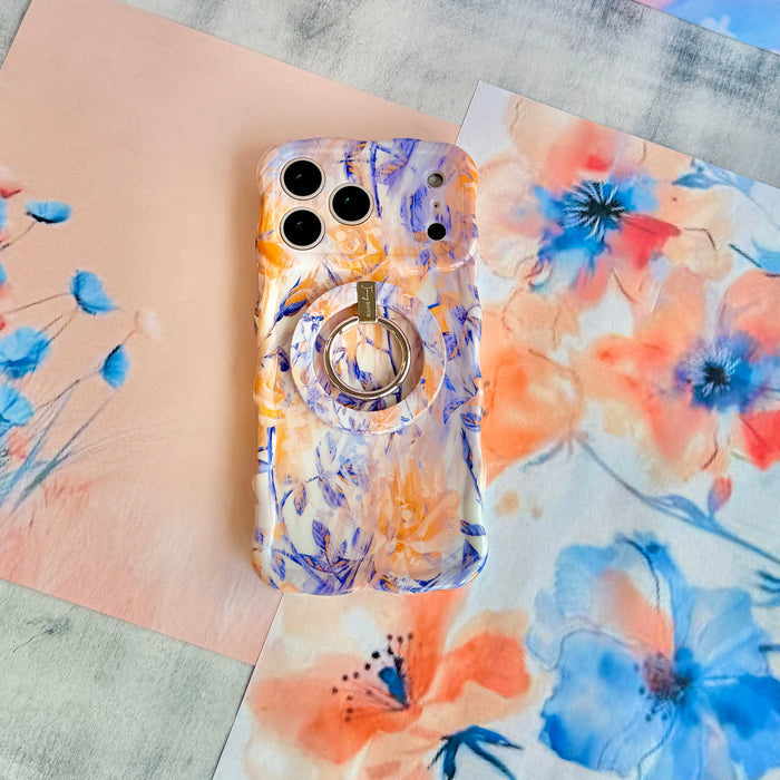 Where Dreams Bloom MagSafe grip ring attached to the matching Where Dreams Bloom iPhone case, styled on a blue and peach watercolor floral backdrop.